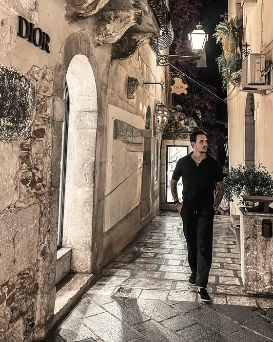 Lucas Steffen caminhando por uma viela iluminada à noite, em Taormina